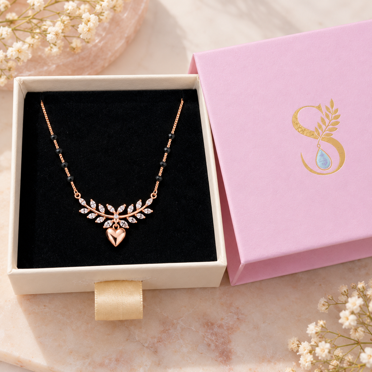 Rose gold infinity mangalsutra resting on black velvet in a Silvanya jewelry box.
