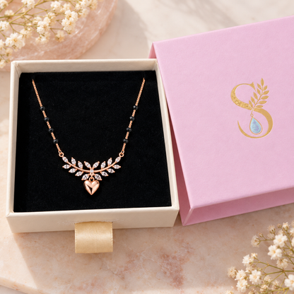 Rose gold infinity mangalsutra resting on black velvet in a Silvanya jewelry box.