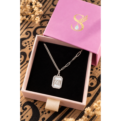 Silver Roman numeral pendant necklace displayed inside Silvanya pink gift box on black velvet.