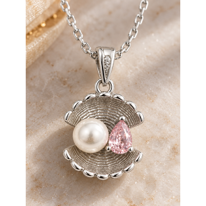 Macro view of the shell pendant, showing the ribbed silver, white pearl, and pink cubic zirconia.