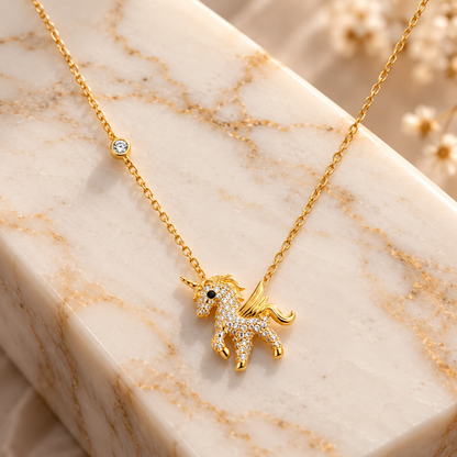 Gold pendant necklace with sparkling stones on an ivory marble block.