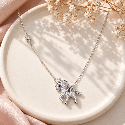 Silver unicorn necklace styled flat on an ivory tray with soft window light and dried flowers.