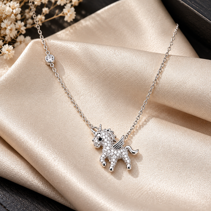 Silver pave unicorn pendant resting on soft champagne silk cloth.