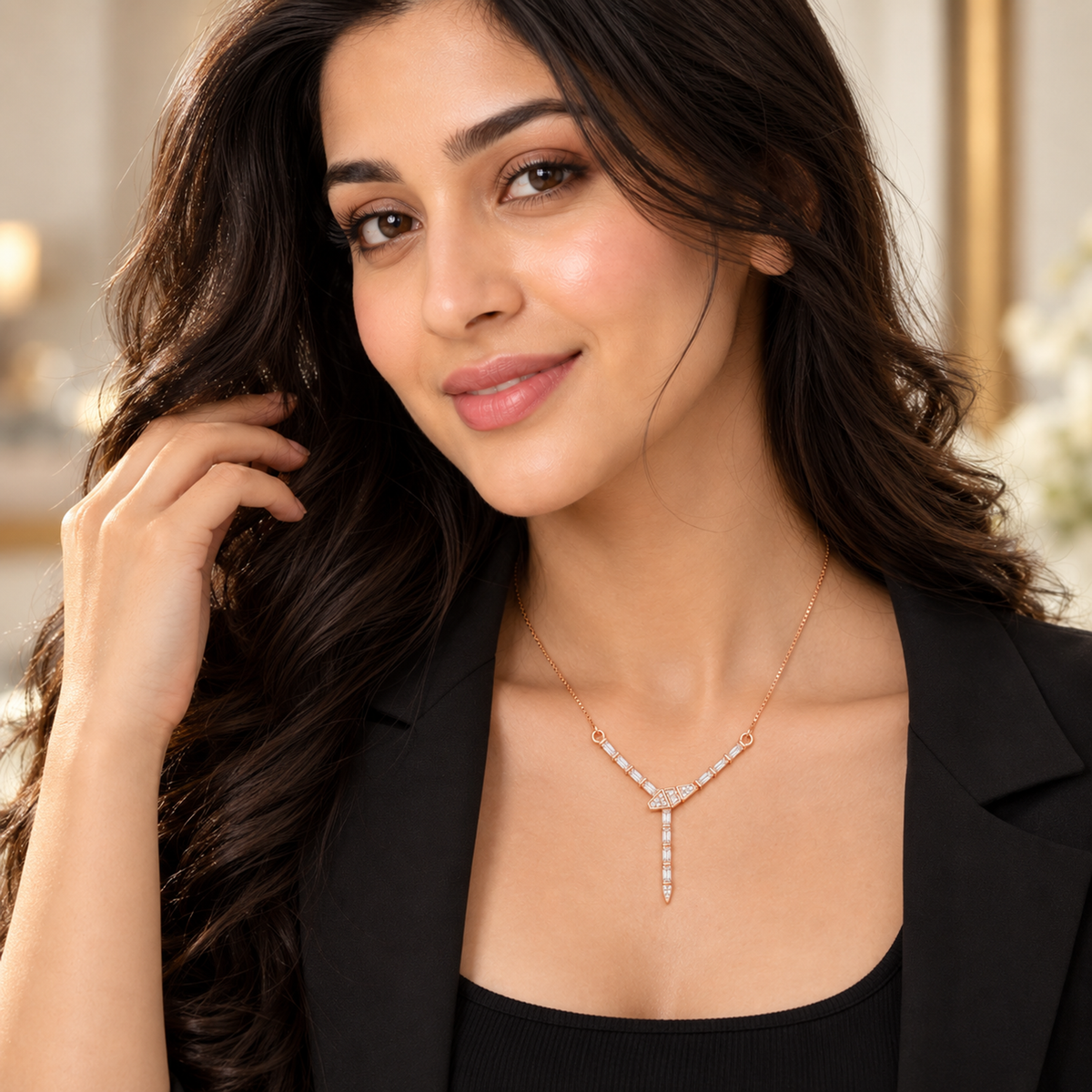 Close-up portrait of a woman in a black blazer wearing a sparkling rose gold Y-drop necklace.