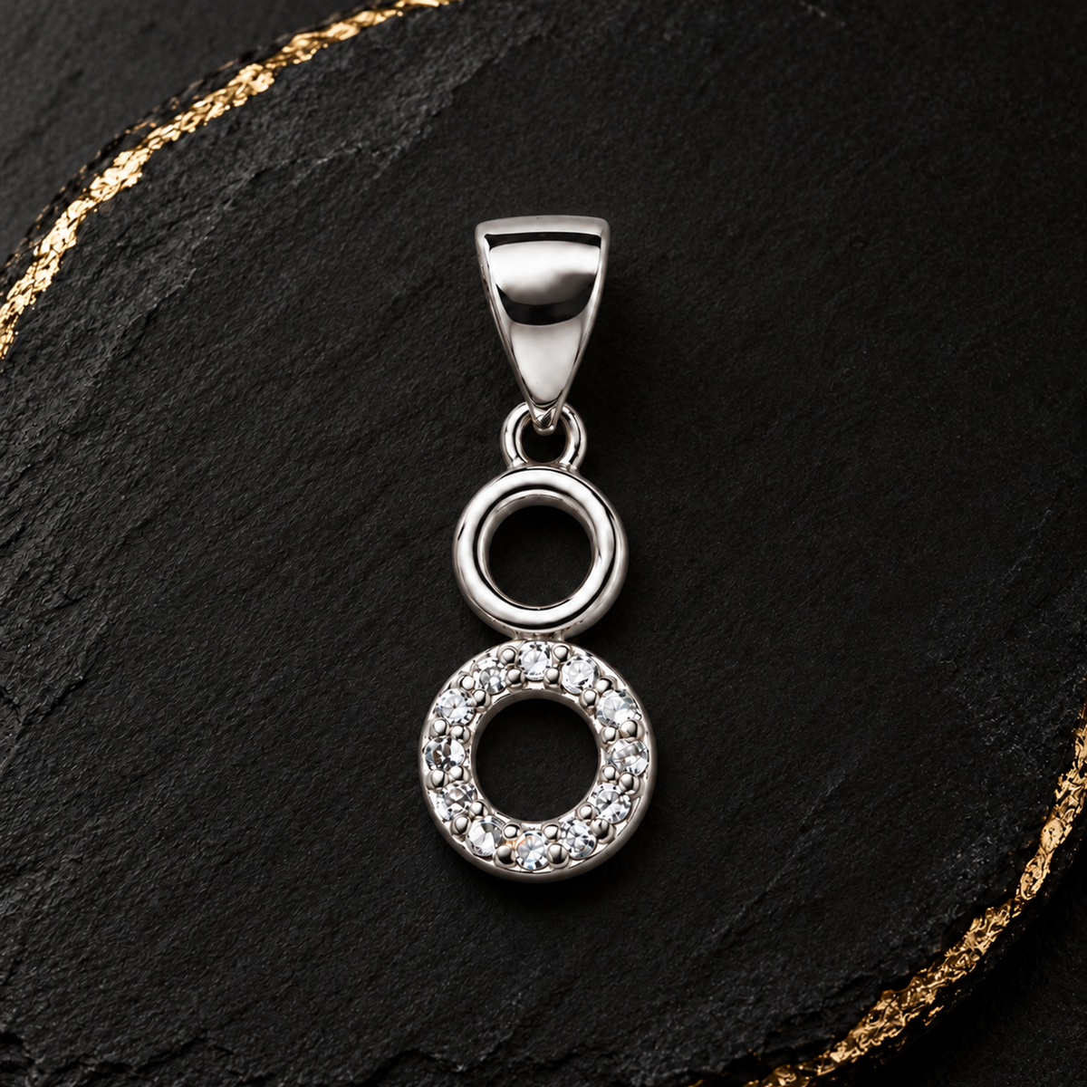 Silver circle pendant resting on blush pink silk and ivory marble.