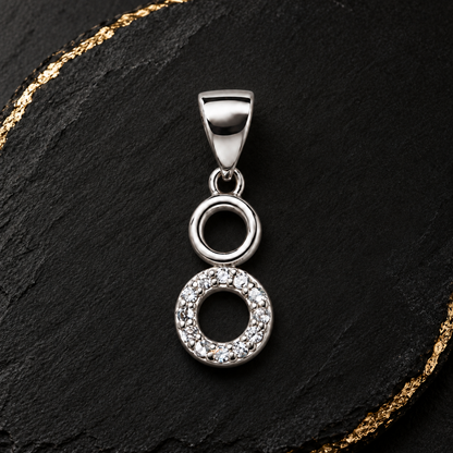 Silver circle pendant resting on blush pink silk and ivory marble.