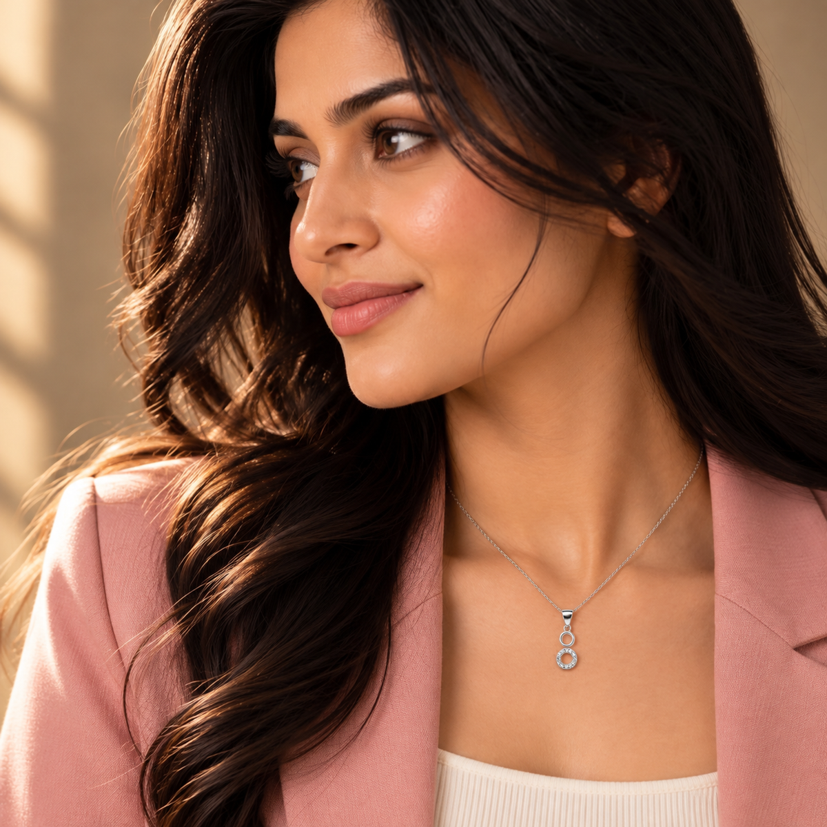 Profile shot of Noya wearing the dual ring pendant with a pink blazer.