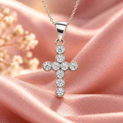 Silver cross pendant nestled in a black velvet cushion inside a pale pink Silvanya gift box.