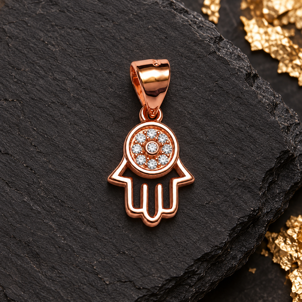 Rose gold Hamsa pendant top-down on matte black slate.