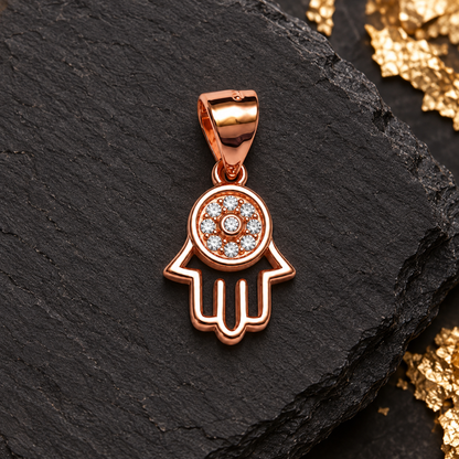 Rose gold Hamsa pendant top-down on matte black slate.
