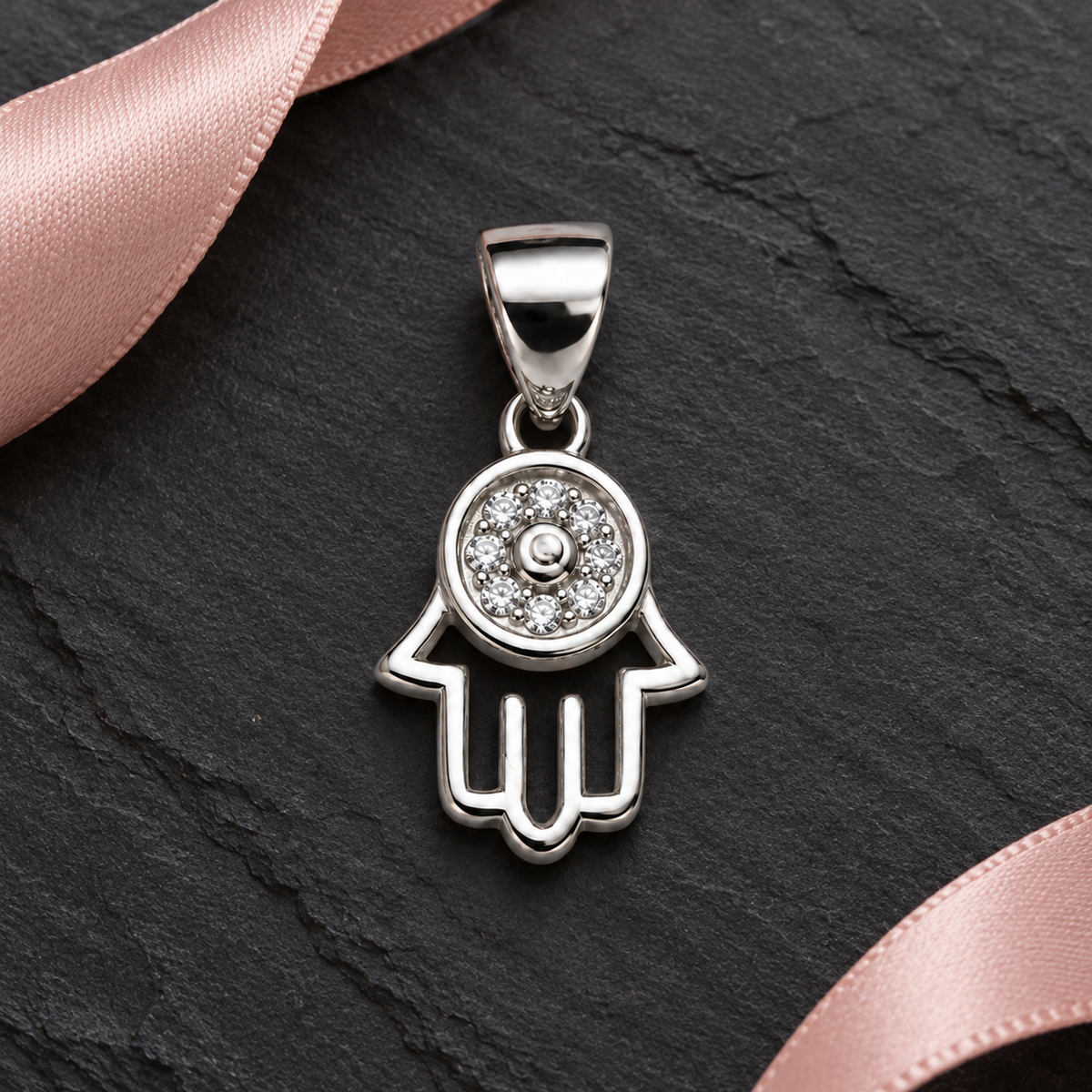 Silver Hamsa pendant styled on textured ivory linen with subtle warm gold accents.