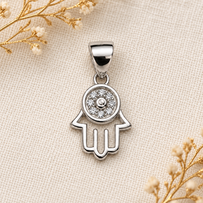 Woman wearing a delicate silver Hamsa pendant resting near her collarbone, dressed in an ivory shirt.
