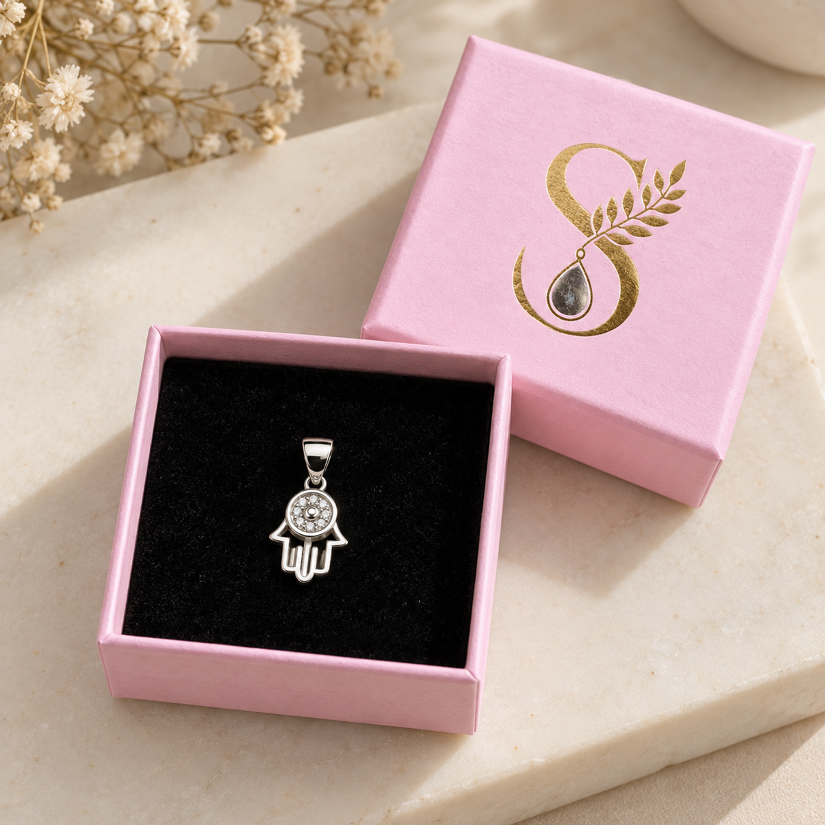 Silver Hamsa pendant presented inside a small pink Silvanya jewellery box with black velvet lining.