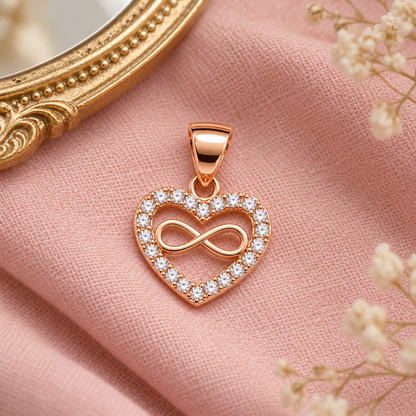 Rose gold heart infinity pendant lying on soft blush pink linen next to a gold antique mirror.