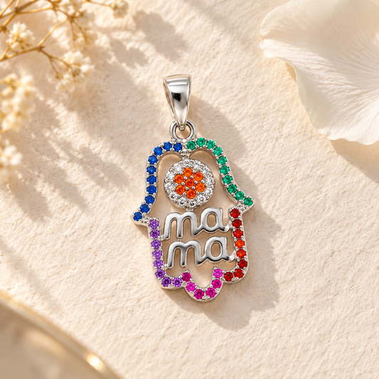 A silver mama Hamsa pendant resting on textured ivory paper beside a delicate white flower petal.
