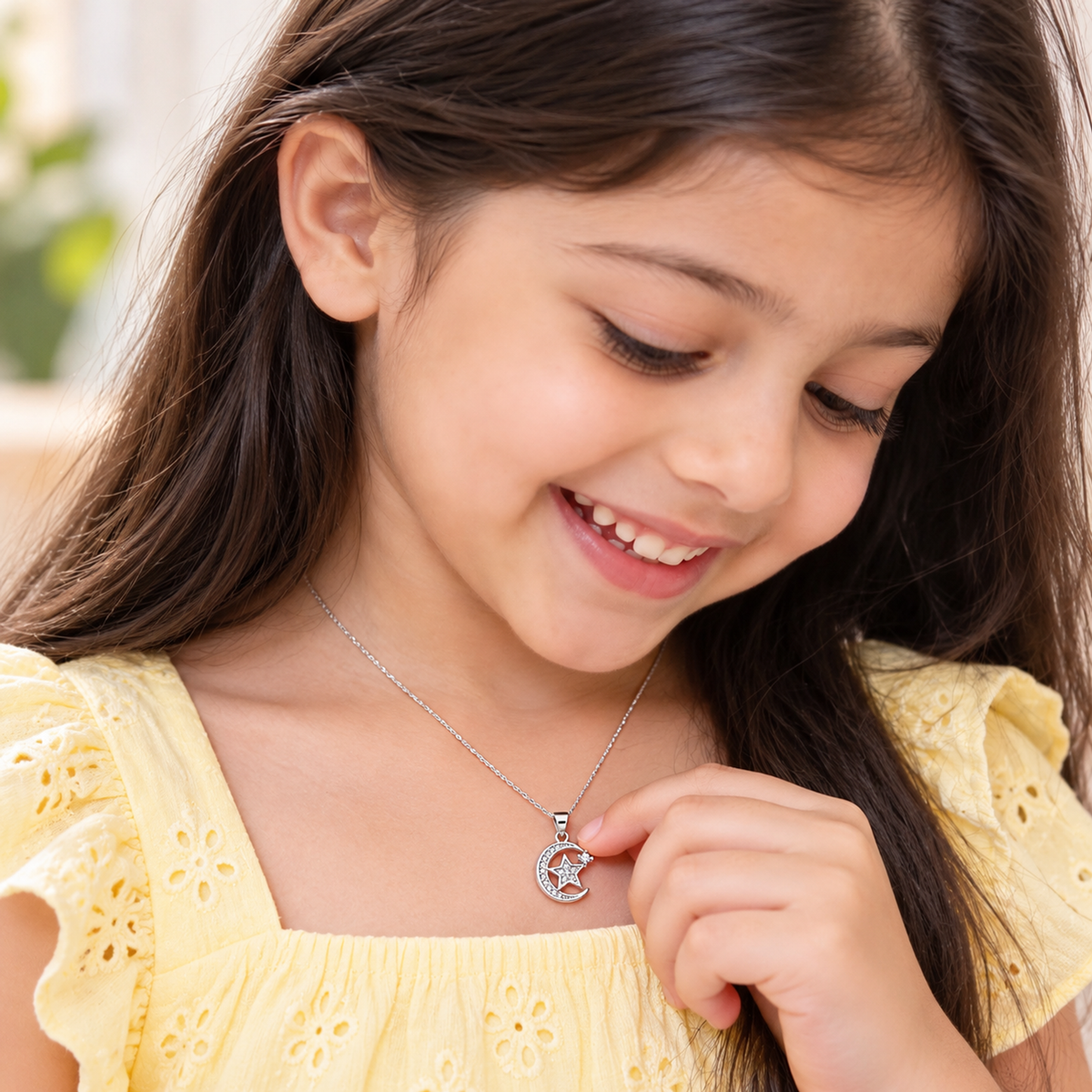 Child wearing the silver crescent moon and star pendant over a pastel yellow dress.