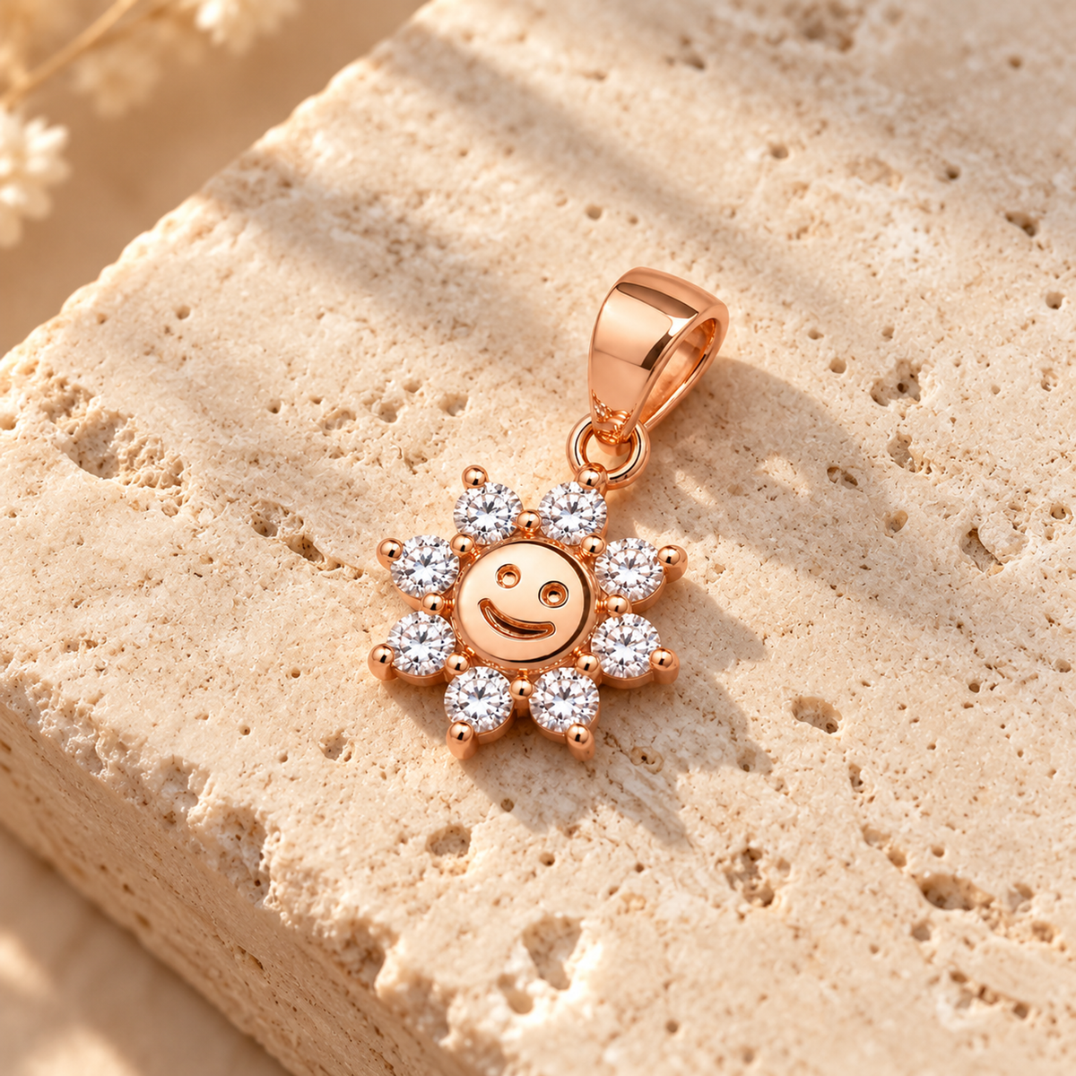 Rose gold smiling sun pendant placed on an ivory travertine stone surface.
