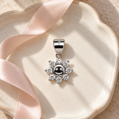 Silver sun pendant resting on dark slate with soft gold accents.