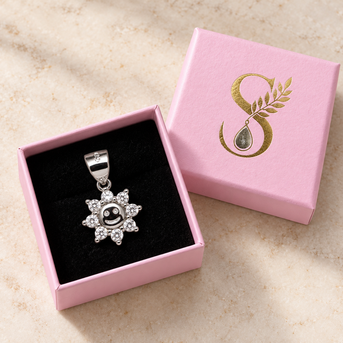 Silver sun pendant resting in a pale pink gift box on black velvet.