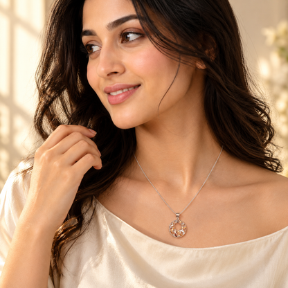 A woman wearing a circular two-tone pendant on a silver chain against her collarbone.