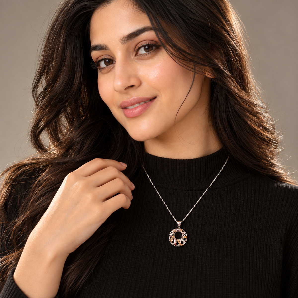 A woman wearing a circular dual-finish pendant styled over a black high-neck sweater.