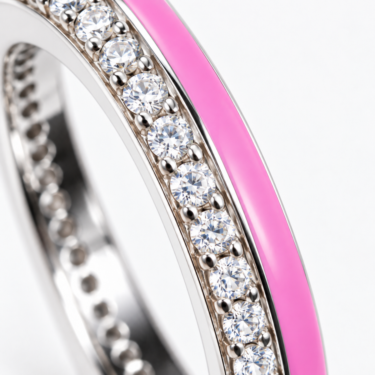 Macro detail shot showing pave cubic zirconia and pink enamel side-by-side on a rhodium silver band.