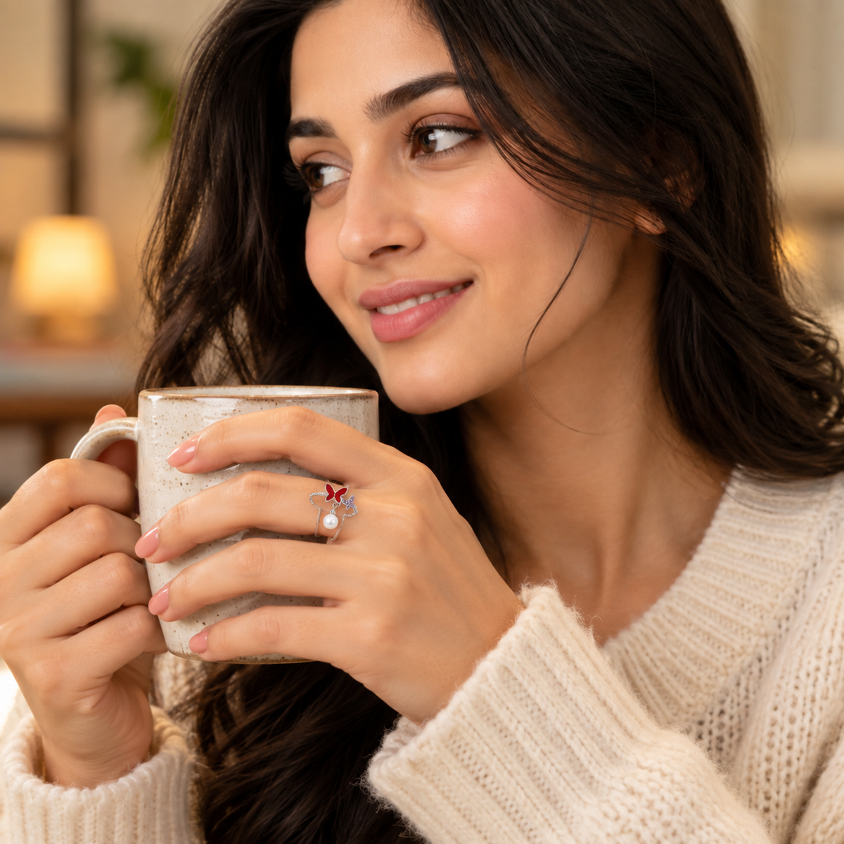 A cozy close-up of a hand wearing the silver butterfly ring while holding a warm ceramic mug.
