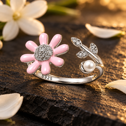 Silver daisy ring with a pearl on a dark slate background accented by small white petals.