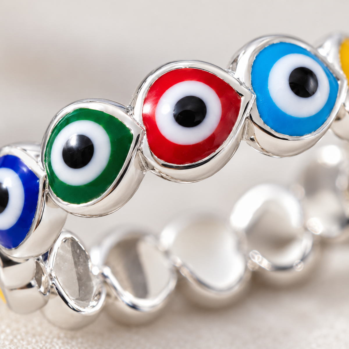 Macro photograph showing the detailed enamel evil eye motifs inside silver heart outlines.