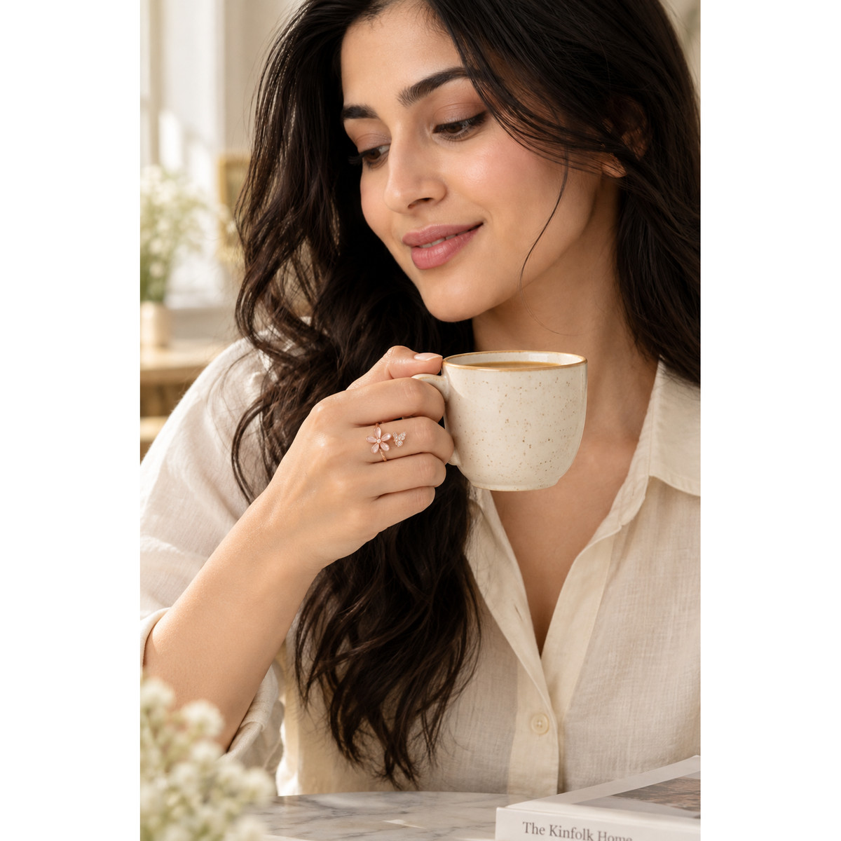 Model wearing rose gold flower and butterfly bypass ring while holding a tea cup.