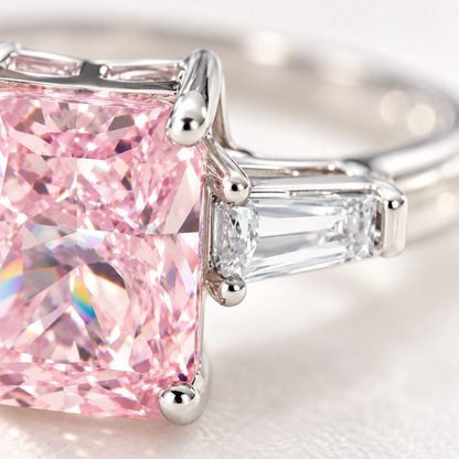 Macro close-up of the four-prong setting and clear baguette stones of a pink gemstone silver ring.