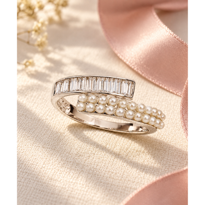 Silver bypass ring resting on ivory linen near a pink ribbon.