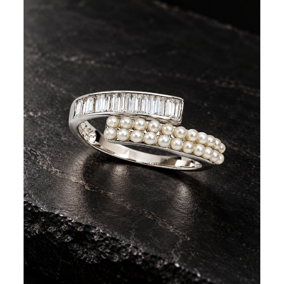 Silver ring with pearls and clear stones on a matte black stone surface.