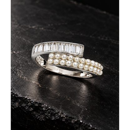 Silver ring with pearls and clear stones on a matte black stone surface.