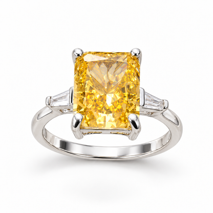 Polished silver ring with a large radiant-cut yellow gemstone and clear shoulder stones on a seamless white background.