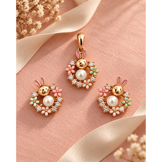 Bunny pendant and matching earrings laid on smooth blush pink linen fabric next to an ivory ribbon.