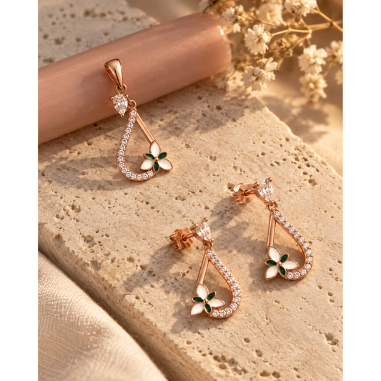 Drop pendant and earrings on ivory stone beside a pink candle and dried bloom.