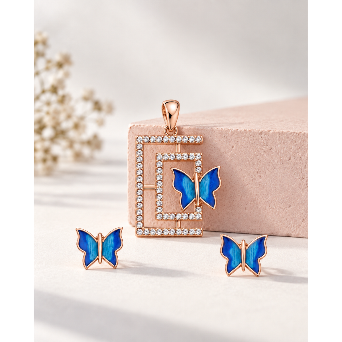 Butterfly pendant standing against a blush pink block with studs in front.